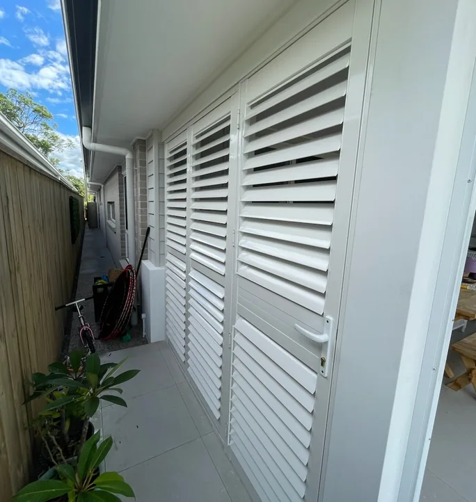 Aluminium shutters enclosing a side walkway