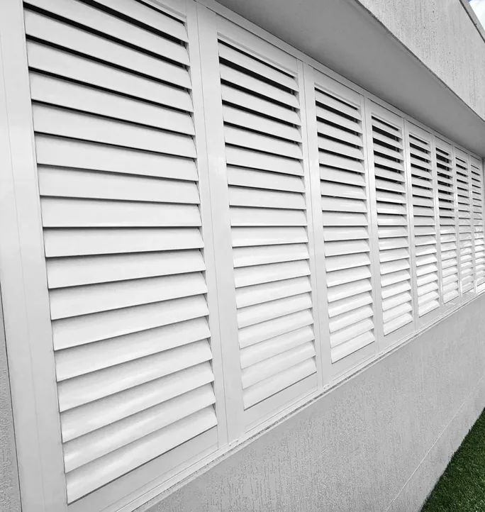 White aluminium shutters along a house