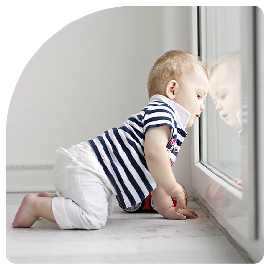 Baby at a window behind a BasiX fall prevention screen