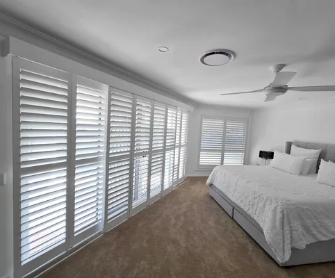 Plantation shutters along a bedroom wall