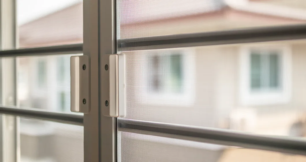 Security screen door close-up with a house behind