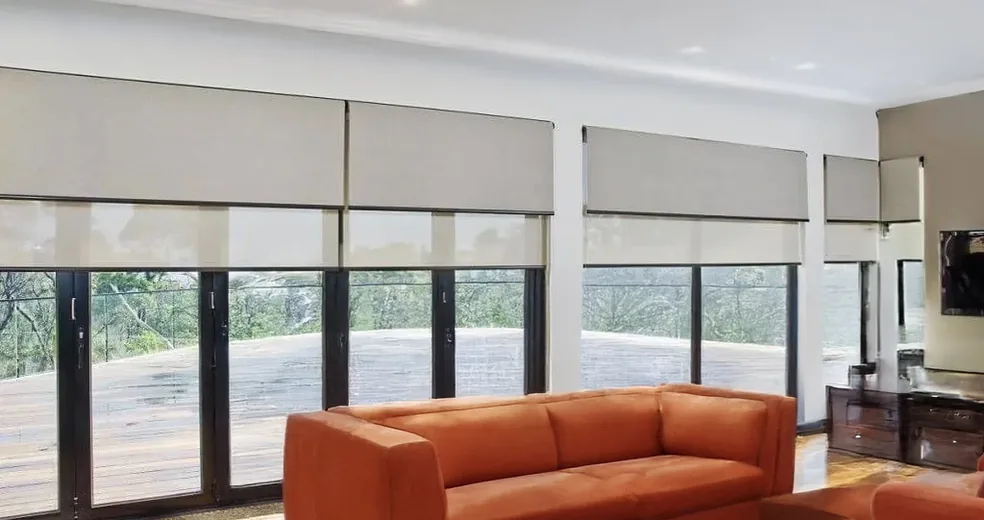 Double roller blinds in a living room with pool views