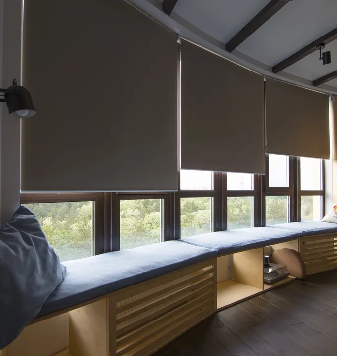 Dark roller blinds across a bank of windows