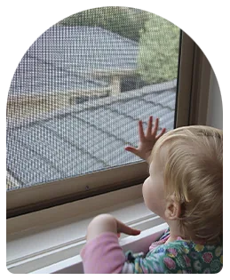 Toddler at a window protected by a BasiX fall prevention screen
