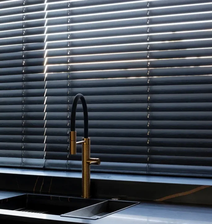 Black Venetian blinds behind a kitchen sink